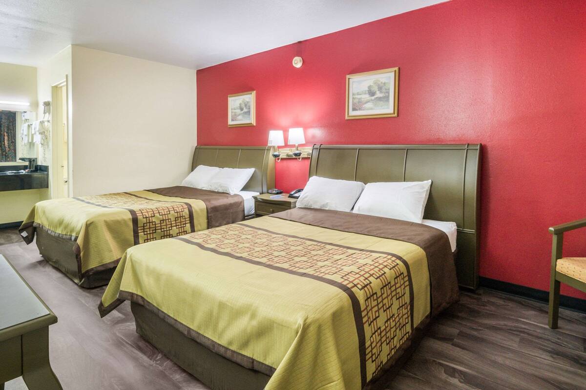 A hotel room with two beds, a desk, and a chair.