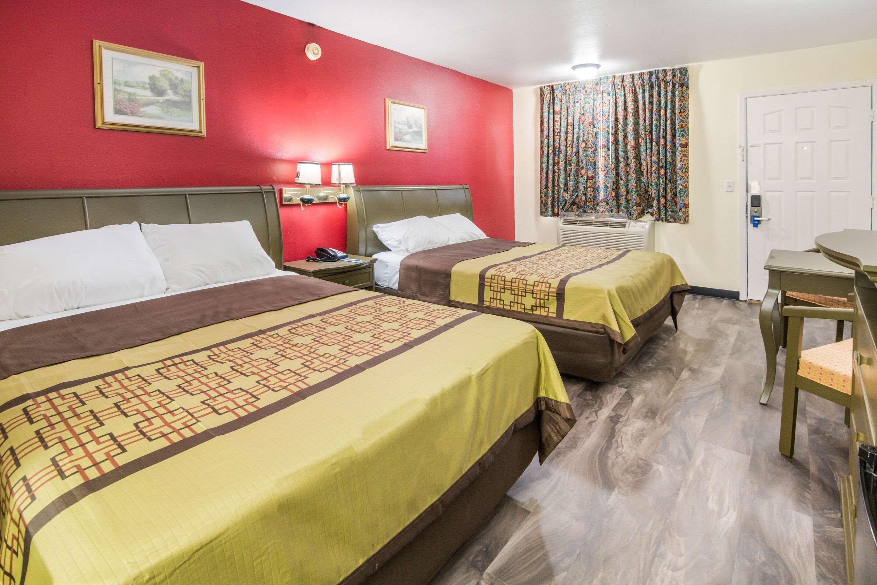 A hotel room with two beds, a desk, and a chair.