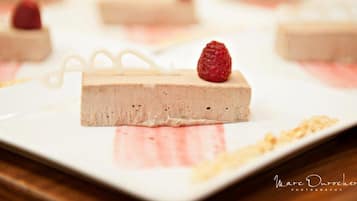 A dessert with a raspberry on top, placed on a white plate.
