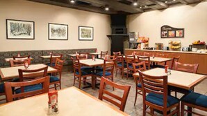 A restaurant interior with wooden tables and chairs, framed artwork on the walls, and a counter with food items. - The Senator Hotel & Conference Centre Timmins (Timmins)