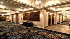 A large, carpeted hall with a patterned floor, a black sofa, and a large wall painting. - The Senator Hotel & Conference Centre Timmins (Timmins)