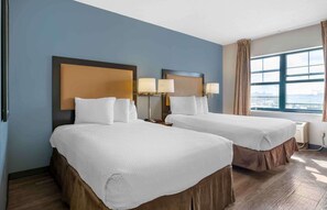 A hotel room with two beds, a large window with a city view, and a wall-mounted air conditioning unit. - Extended Stay America Suites Chicago Midway (Chicago)