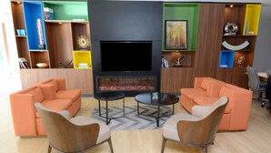 Een moderne woonkamer met oranje banken, een flatscreen televisie en een open haard.