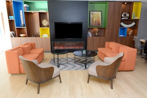 Una sala moderna con sofás naranjas, un televisor de pantalla plana y una chimenea.