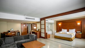 Een moderne hotelkamer met een groot bed, een slaapbank, een bureau en een badkamer met een bad.