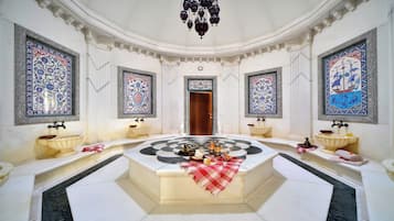 Ein luxuriöses Badezimmer mit aufwendigen Fliesen, einem zentralen Marmorwaschbecken und einer Chandelier.