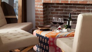 Een gezellige woonkamer met een metselwerk openhaard, een flatscreen televisie erboven en twee comfortabele fauteuils.