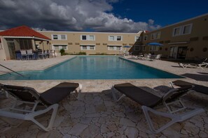 Relax by the clear pool surrounded by lounge chairs and umbrellas.