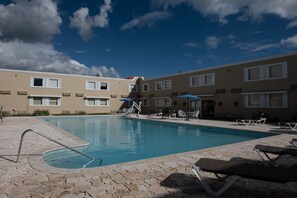 Relax by the pool surrounded by lounge chairs and umbrellas.