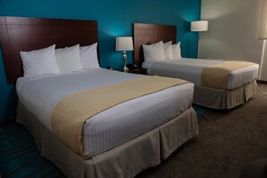 Two plush beds with wooden headboards and crisp white bedding, set against a vibrant accent wall.