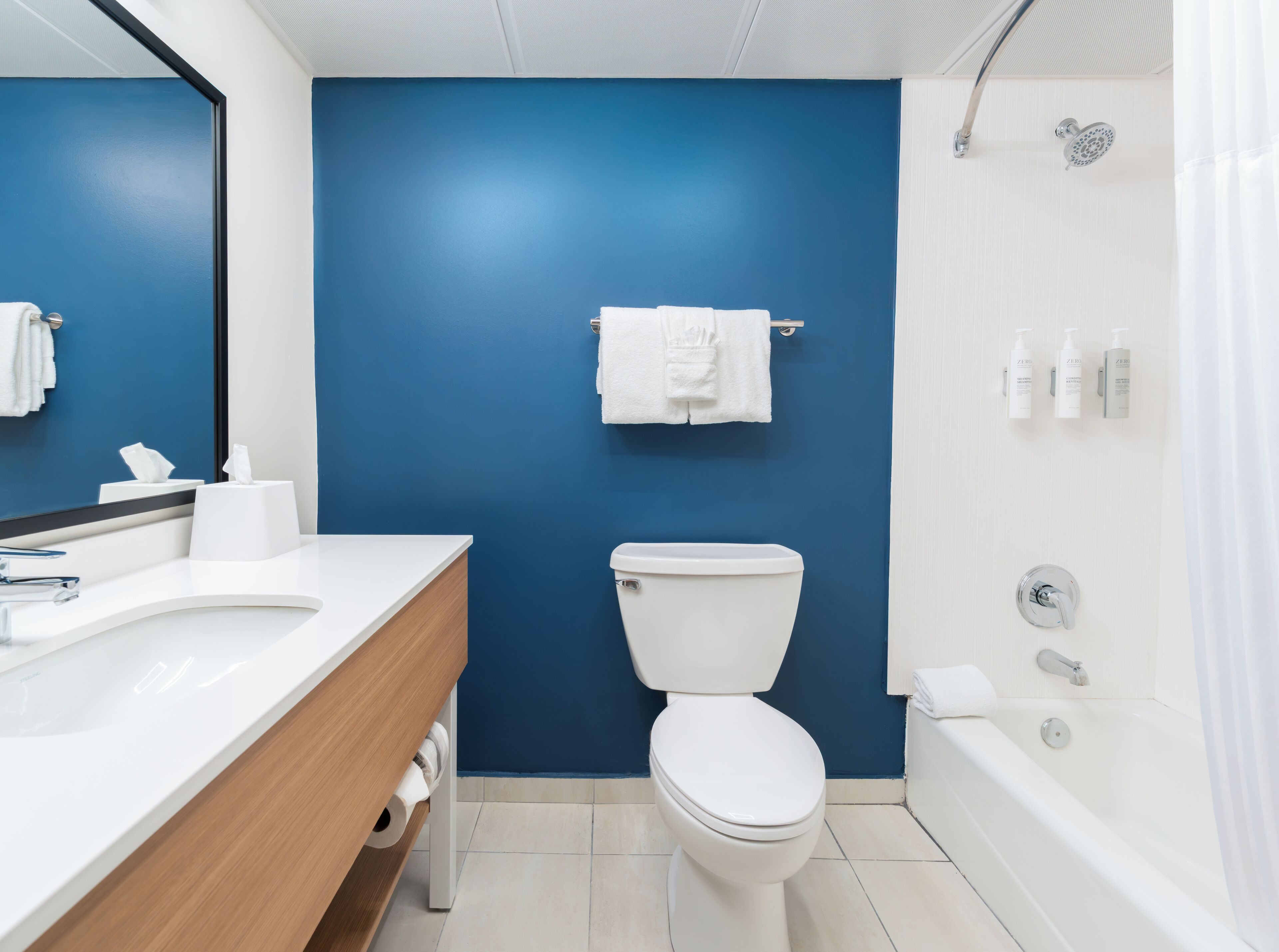 Un baño con pared azul, inodoro blanco y bañera.