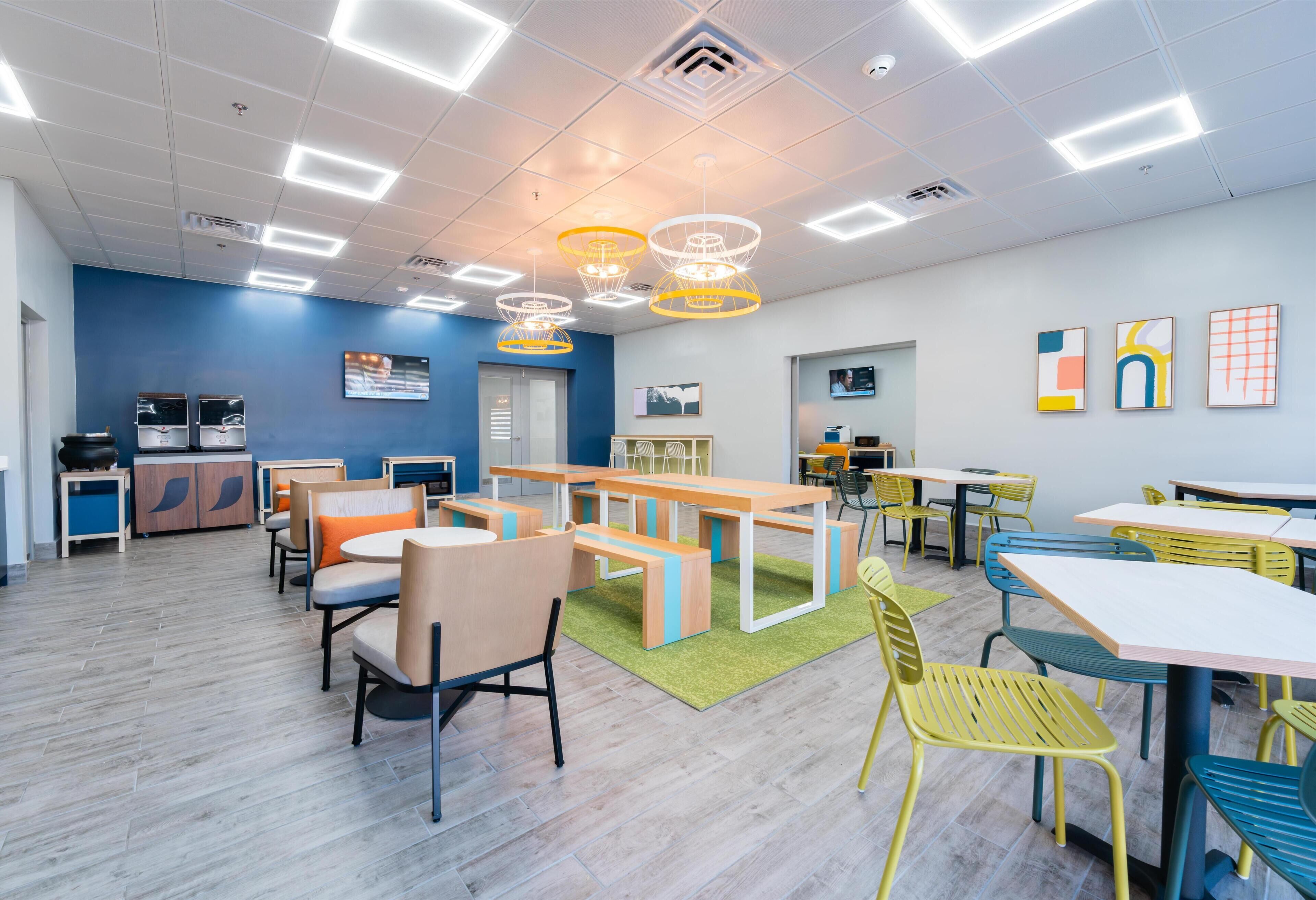 A modern interior with a blue accent wall, multiple seating areas, and contemporary lighting fixtures.