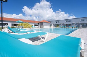 Una piscina al aire libre, sillones reclinables de piscina