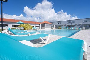 Una piscina al aire libre, sillones reclinables de piscina