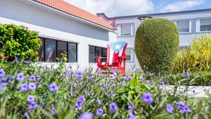 Une maison à l’extérieur rouge et blanc, avec un drapeau et une chaise décorée d’un drapeau.