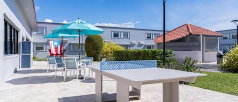 An outdoor patio with a table and chairs, a blue umbrella, and a flag.