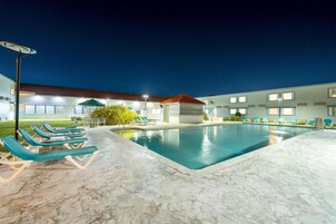 Una piscina al aire libre, sillones reclinables de piscina
