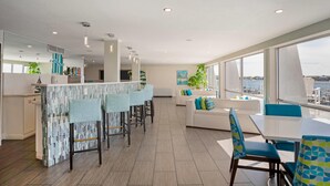 A modern interior with a kitchen, dining area, and seating by large windows. - Inn on Destin Harbor, an Ascend Collection Hotel (Destin)