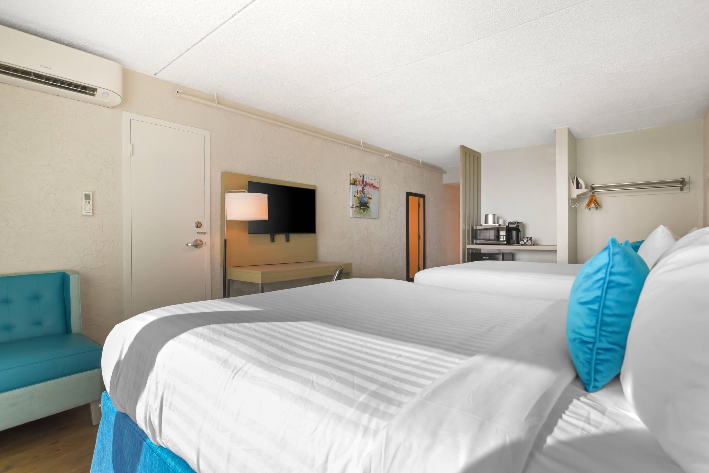 A hotel room with a bed, a desk, a chair, a TV, and a bathroom.