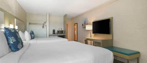 A hotel room with two beds, a desk, a television, and a bathroom.