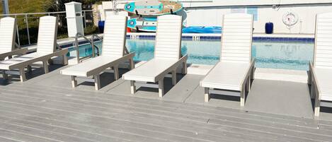 A poolside area with lounge chairs and a sign indicating a 5 ft depth.