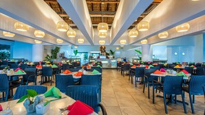 A spacious restaurant with high ceilings, wicker chairs, and tables set with colorful napkins.