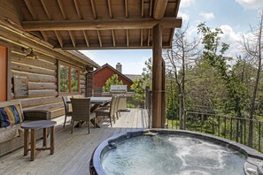 A wooden deck with a hot tub, outdoor seating, and a view of the surrounding forest. - Hilton Grand Vac Club Wilderness Club at Big Cedar Ridgedale (Ridgedale)