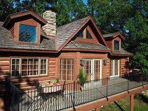 A log cabin with a porch, a dining table, and chairs. - Hilton Grand Vac Club Wilderness Club at Big Cedar Ridgedale (Ridgedale)