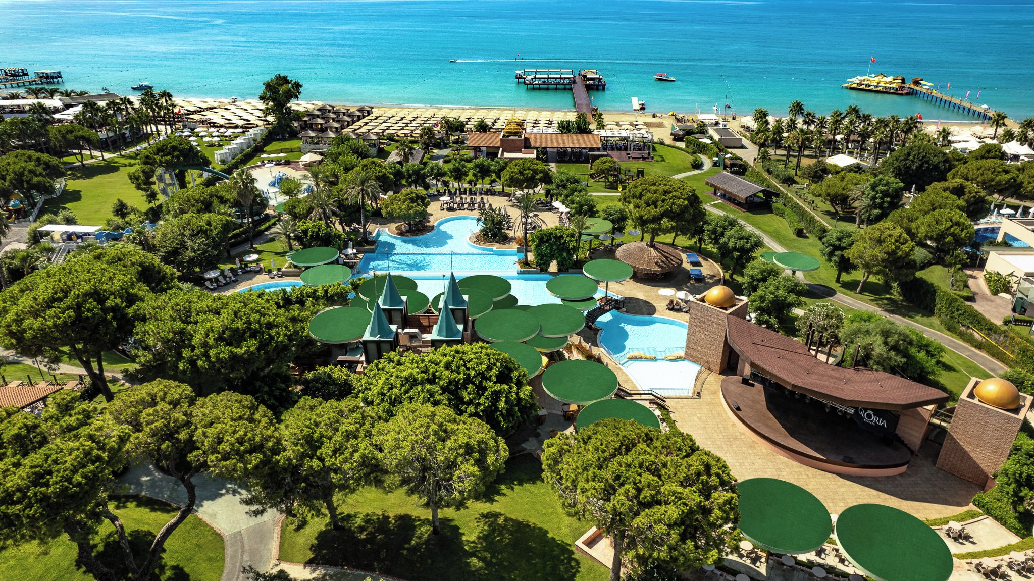 A resort with multiple swimming pools, a beach area, and a pier extending into the sea.