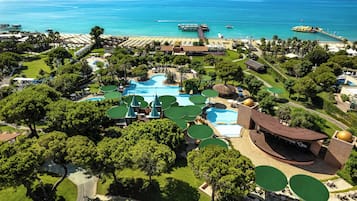 Un resort con múltiples piscinas, una zona de playa y un muelle que se adentra en el mar.