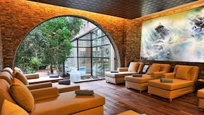 A modern spa area with leather sofas, a large arched window, and a painting on the wall. - Gloria Verde Resort - All Inclusive (Serik)