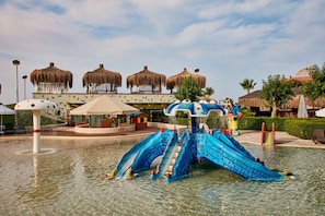 A water park with a blue slide and thatched-roof structures.