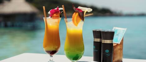 Two cocktails on a table with a view of the sea.