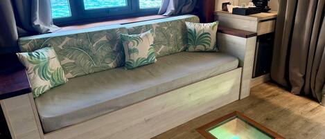 A room with a sofa, a coffee maker, and a view of the ocean.