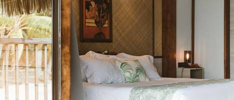 A bedroom with a bed, a painting, a nightstand, and a view of the outdoors.