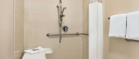 A shower area with a grab bar, a white towel rack, and a white towel on the rack.