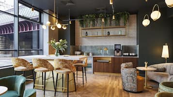 A modern bar area with a marble countertop, bar stools, and a variety of glassware.