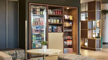 A modern lounge area with a vending machine, seating, and a bookshelf.