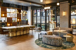 A modern lounge area with a bar, seating arrangements, and a large window providing a view of the outside.