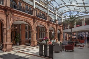 A spacious lobby with a glass ceiling, multiple levels, and a central seating area with modern furniture. - The Crown London, WorldHotels Distinctive (London)