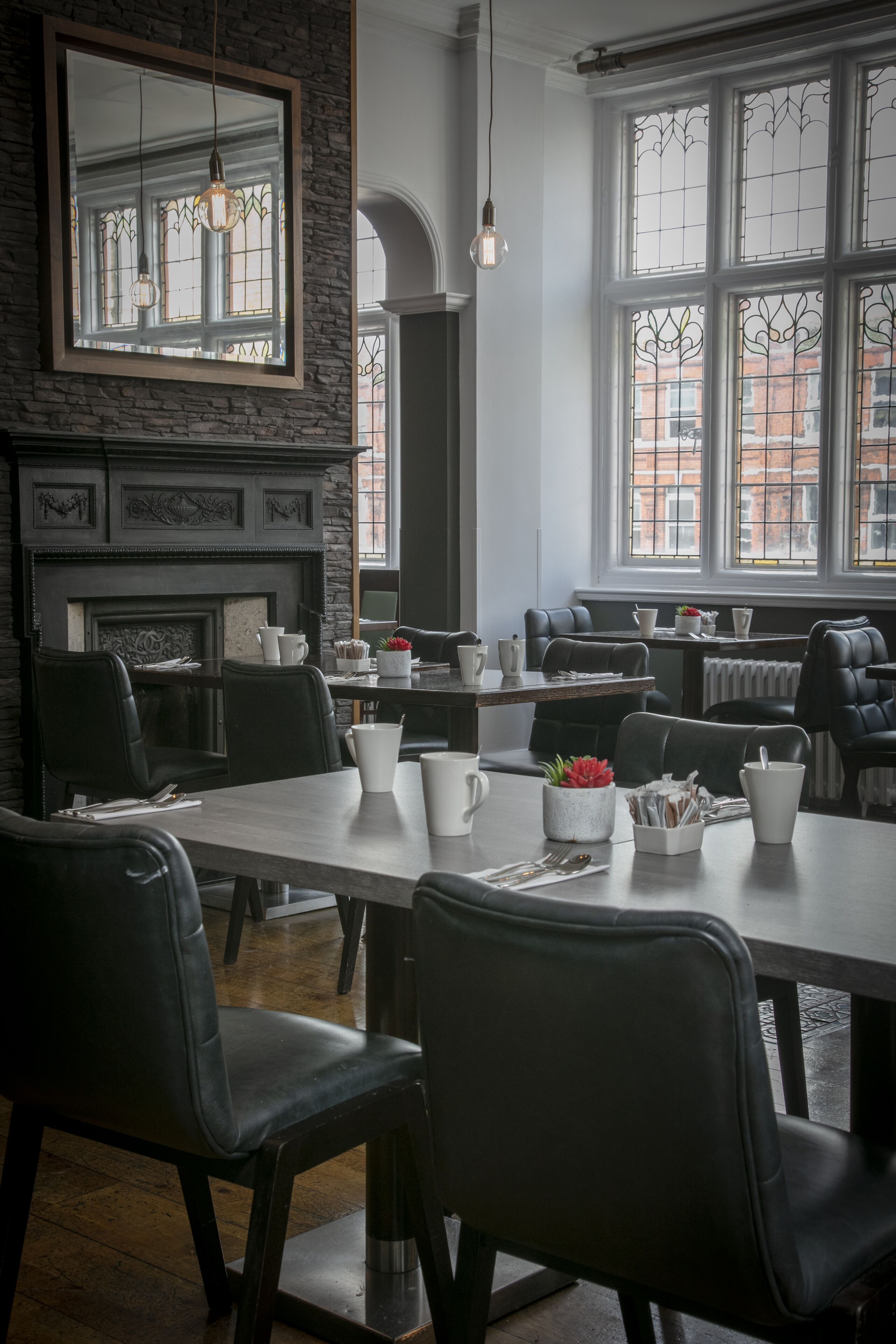 A dining area with a fireplace, large windows, and leather seating.