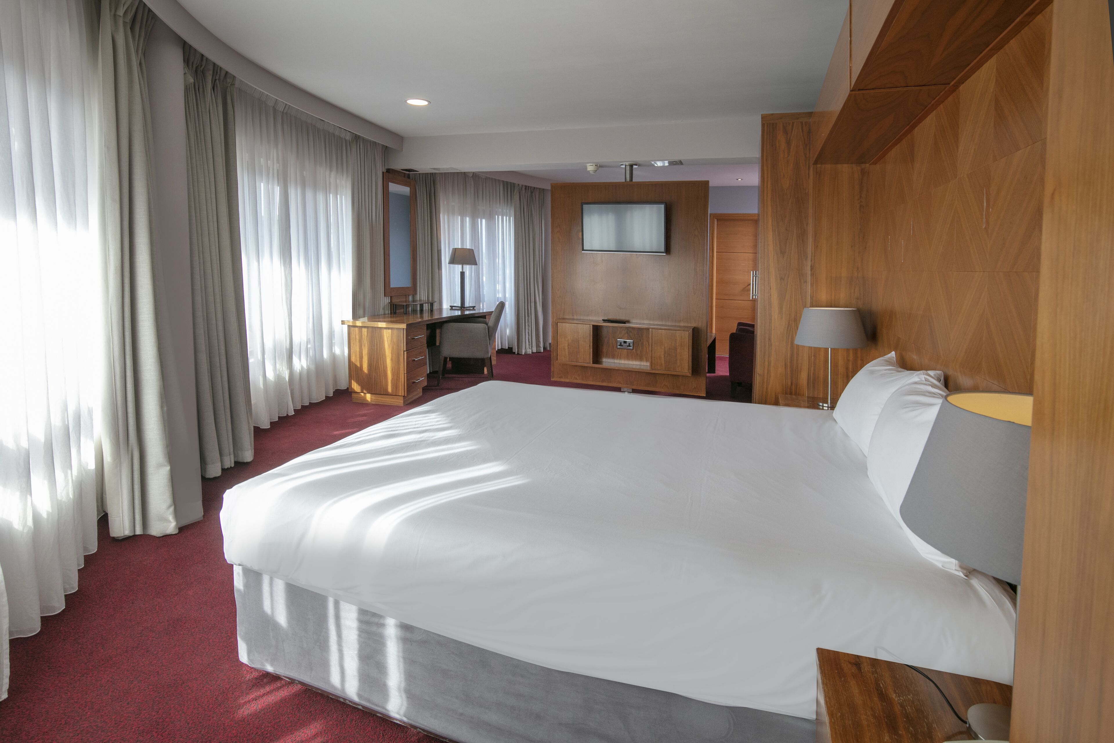 Ein Hotelzimmer mit einem großen Bett, einem Schreibtisch, einem Fernseher und einem Kleiderschrank.