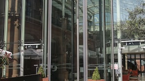 Ein moderner Glas-Eingangsbereich des The Crown Hotels in London, mit einer Drehtür und freiem Blick ins Innere.