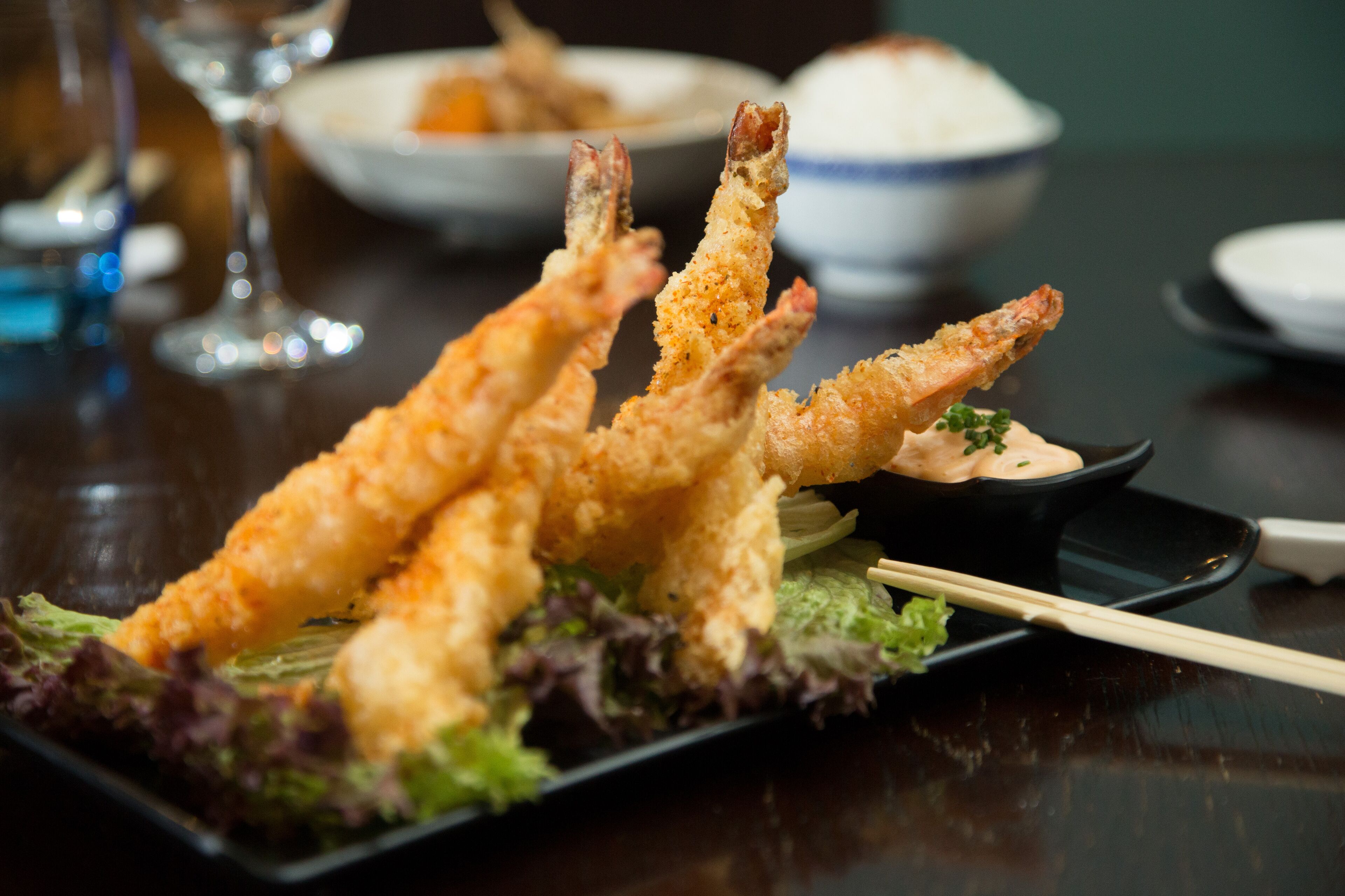 A plate of tempura shrimp with a side of dipping sauce and salad.