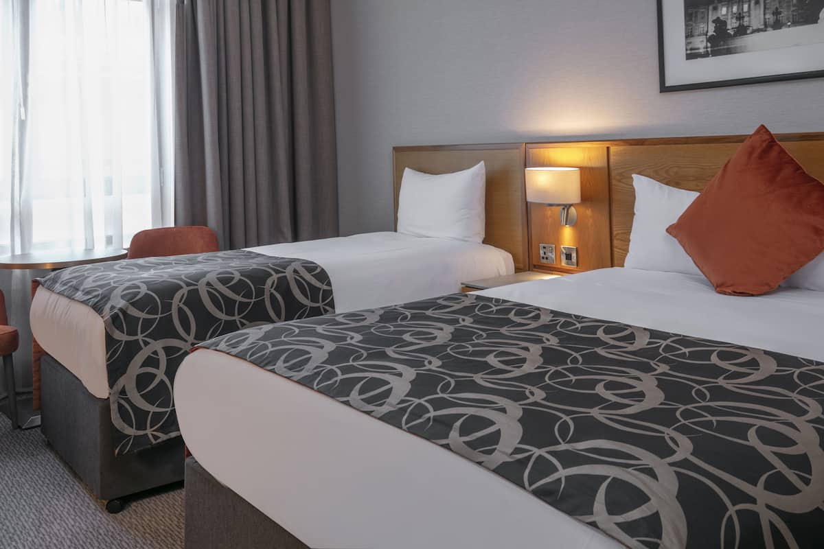 A hotel room with two beds, a desk, and a chair.