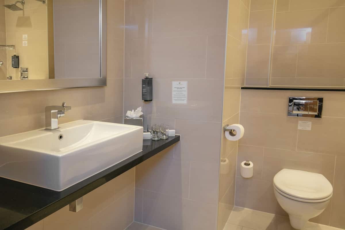 A modern bathroom with a large sink, mirror, toilet, and shower area.