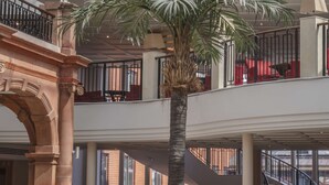 Eine geräumige Lobby mit einer Palme, Sitzgelegenheiten und einer Treppe.
