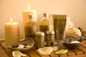 A wooden table with candles, essential oils, and a bowl of white flowers. - Milano & Helvetia (Riccione)