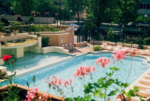 A swimming pool with a waterfall feature, surrounded by lounge chairs and potted plants. - Milano & Helvetia (Riccione)