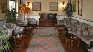 A traditional living room with striped sofas, a central rug, and a television.